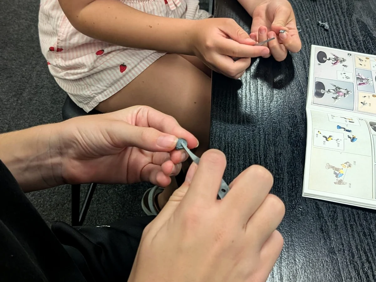 Hands preparing miniature components during a tabletop hobby session.